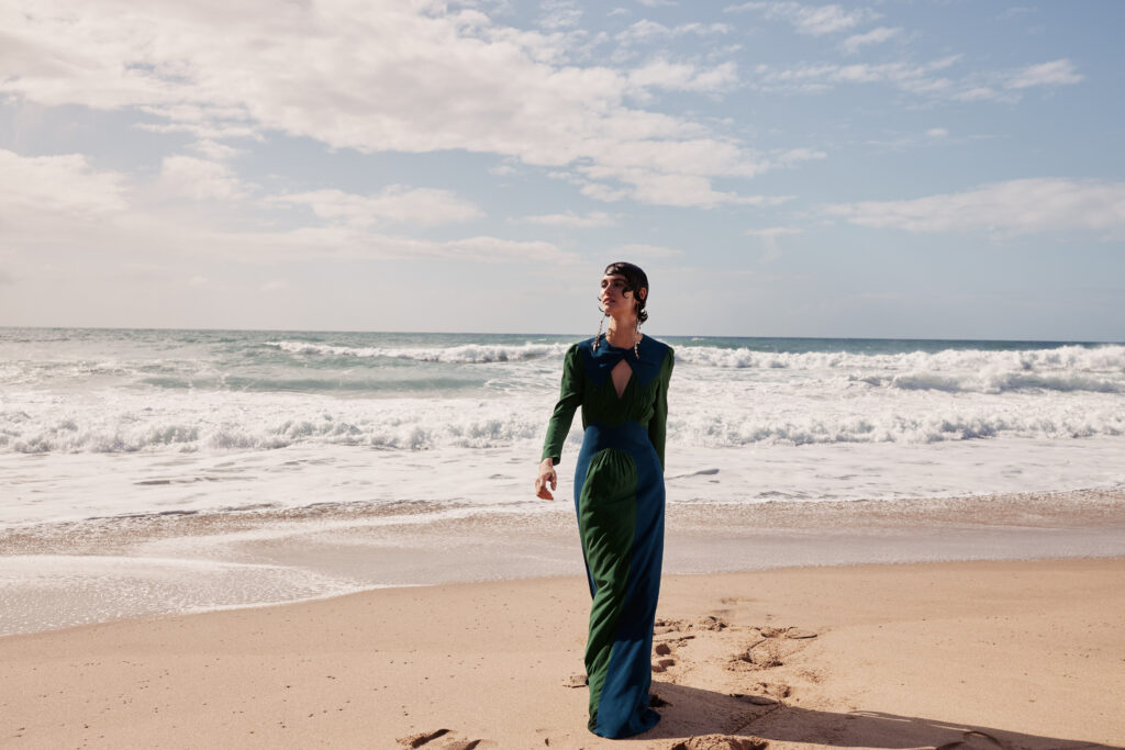 Fashion model in green dress walking along the beach